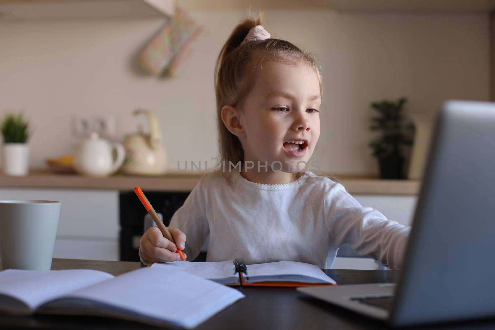 Smiling little girl handwrite study online using laptop at home, cute happy small child take Internet web lesson or class on PC. by tsyhun