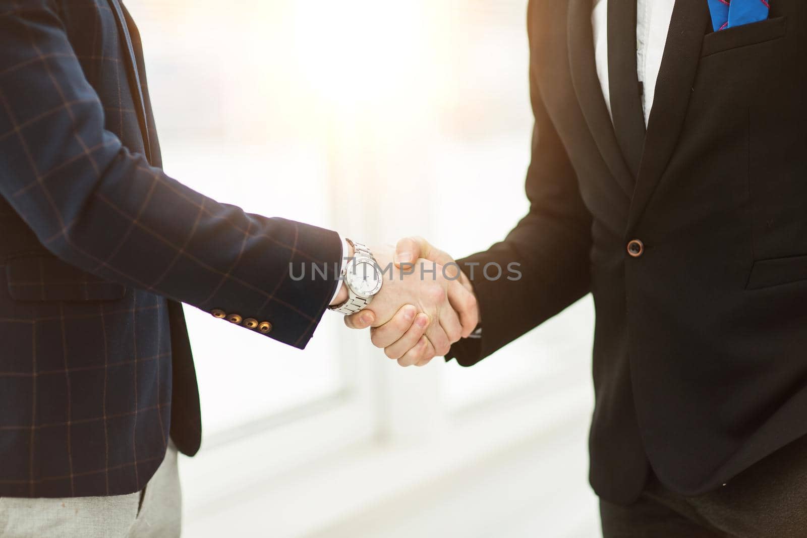 in the foreground - handshake of business partners on background of window in modern office.the photo has a empty space for your text