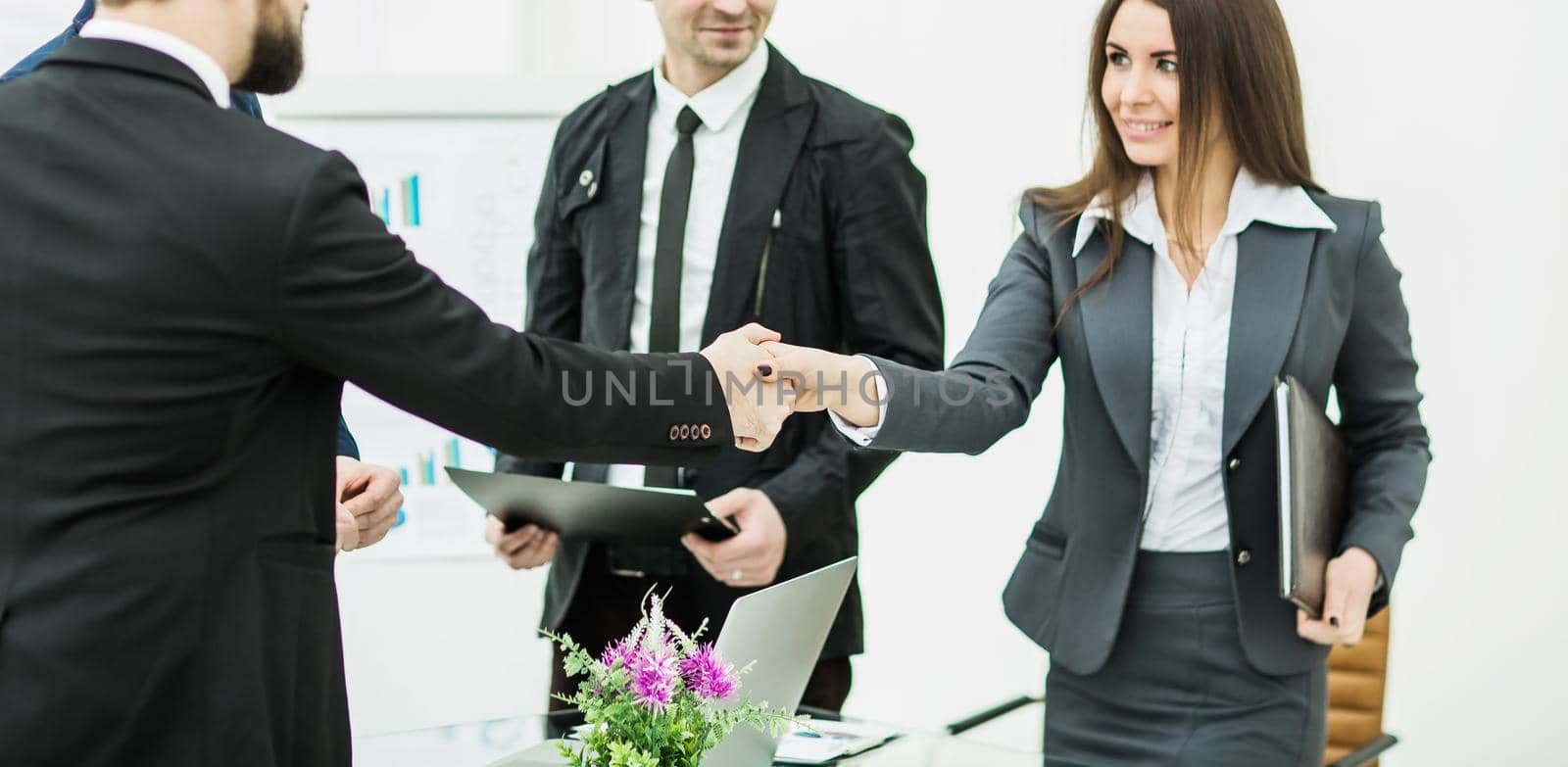 closeup of a successful handshake business partners after signing the contract in the workplace in a modern office