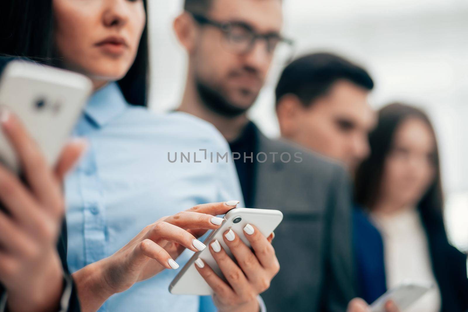 close up. a group of young business people reading messages on their smartphones