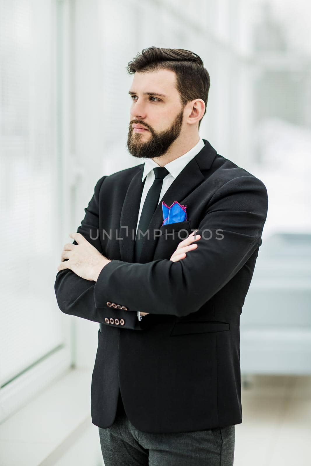 portrait of successful businessman standing near a window in bright office.the photo has a empty space for your text