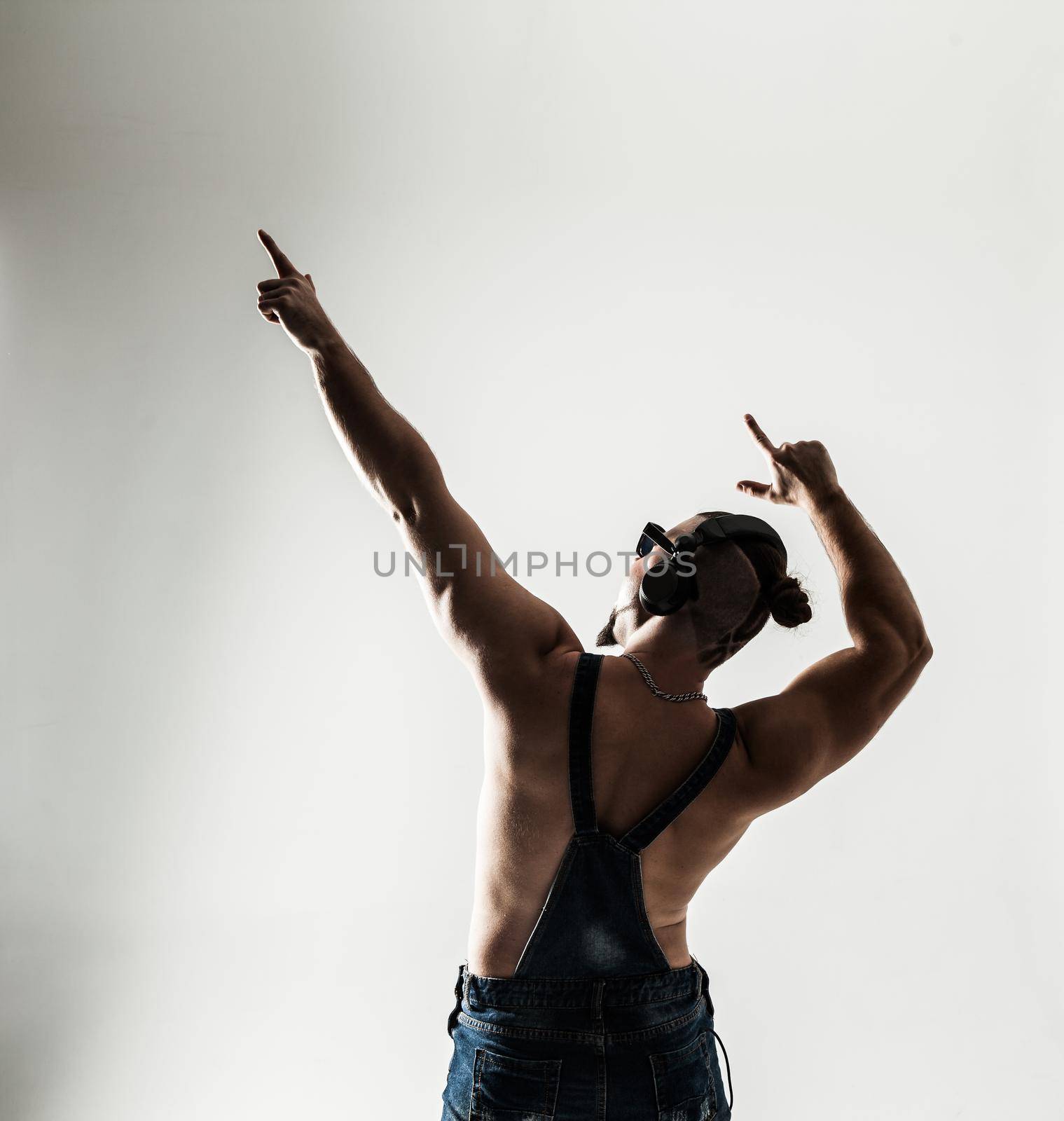 rapper shirtless with headphones and stylish hair and my hands up on a light background . the photo has a empty space for your text