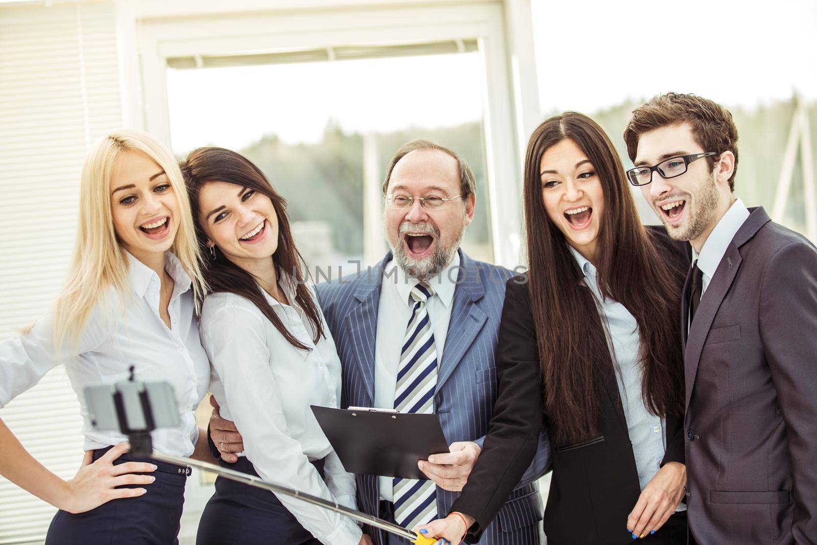 happy business team makes a selfie with his boss standing near the window in the office