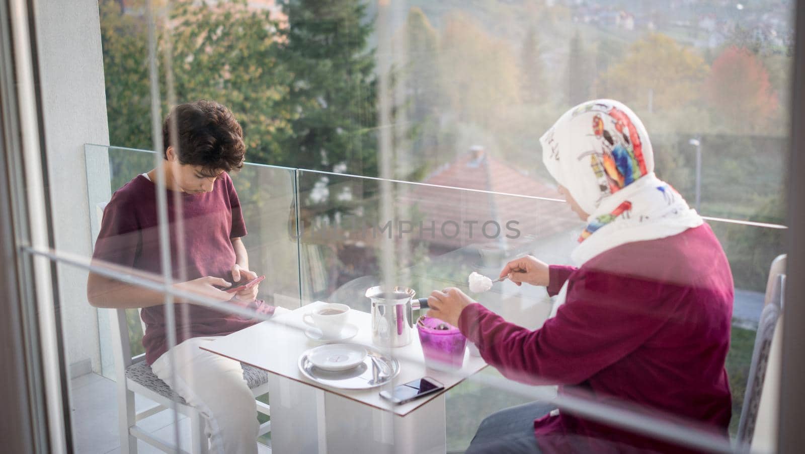 Mother and son enjoying drinking tea on balcony by Zurijeta