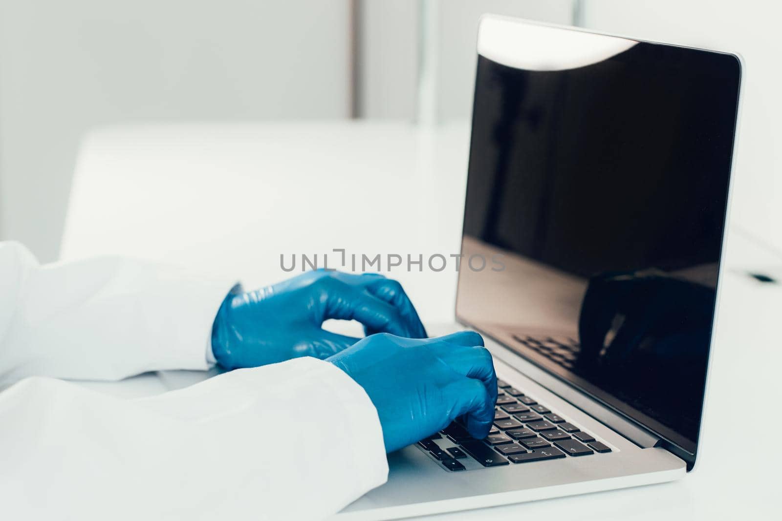 close up. doctor in protective gloves typing on a laptop . by SmartPhotoLab