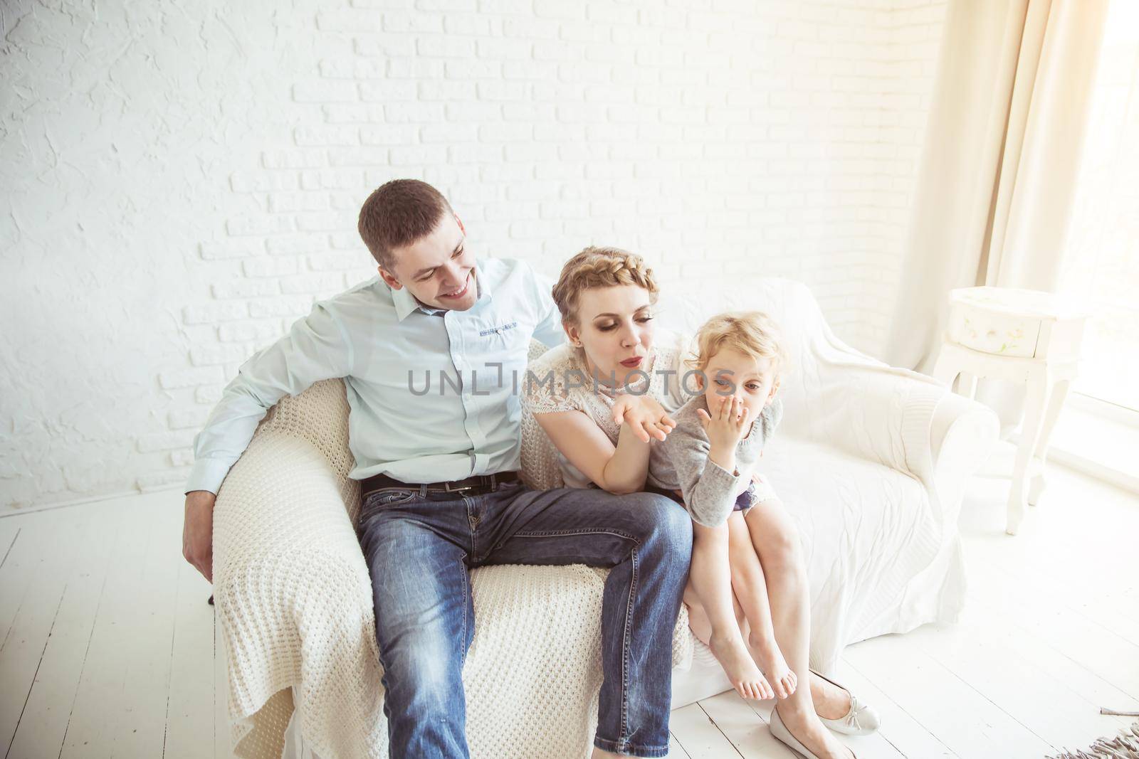 happy parents and five year old daughter sitting on the couch in the living room