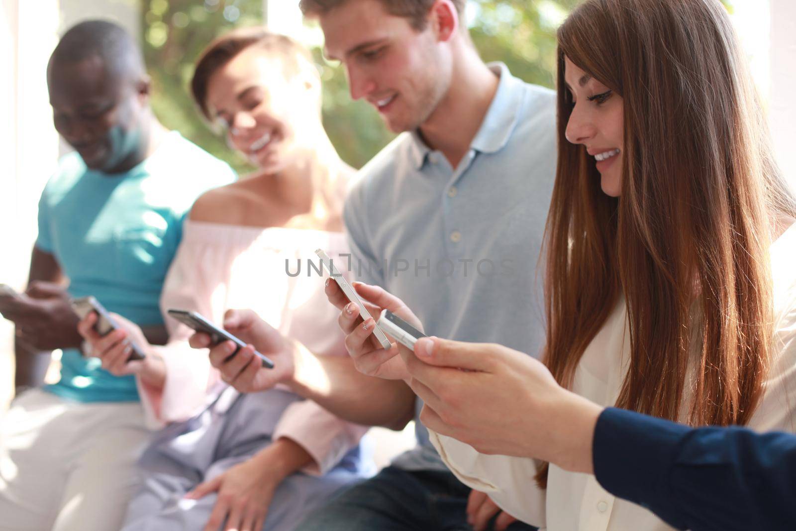 Group of students watching smartphones. Young people addiction to new technology trends. by tsyhun