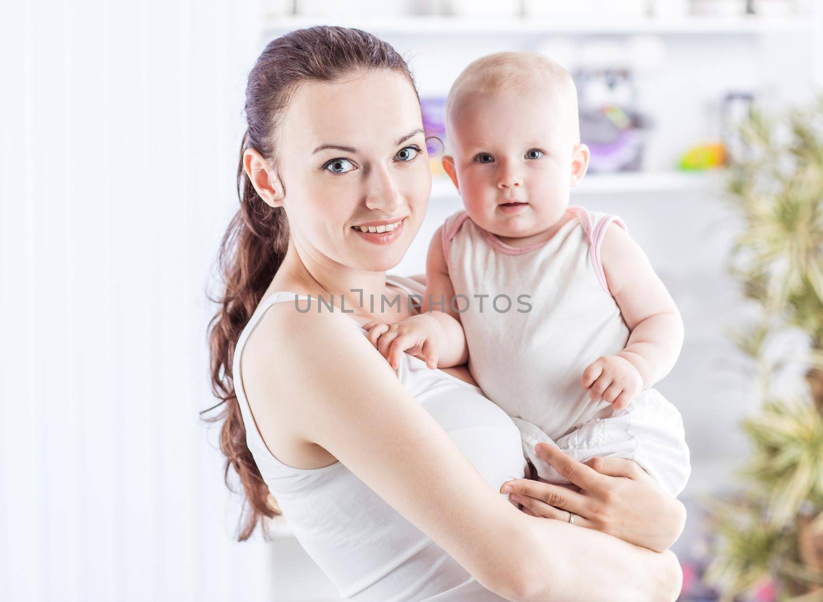 happy mother with a year-old baby in her arms on the background of a child's room.the photo has a empty space for your text
