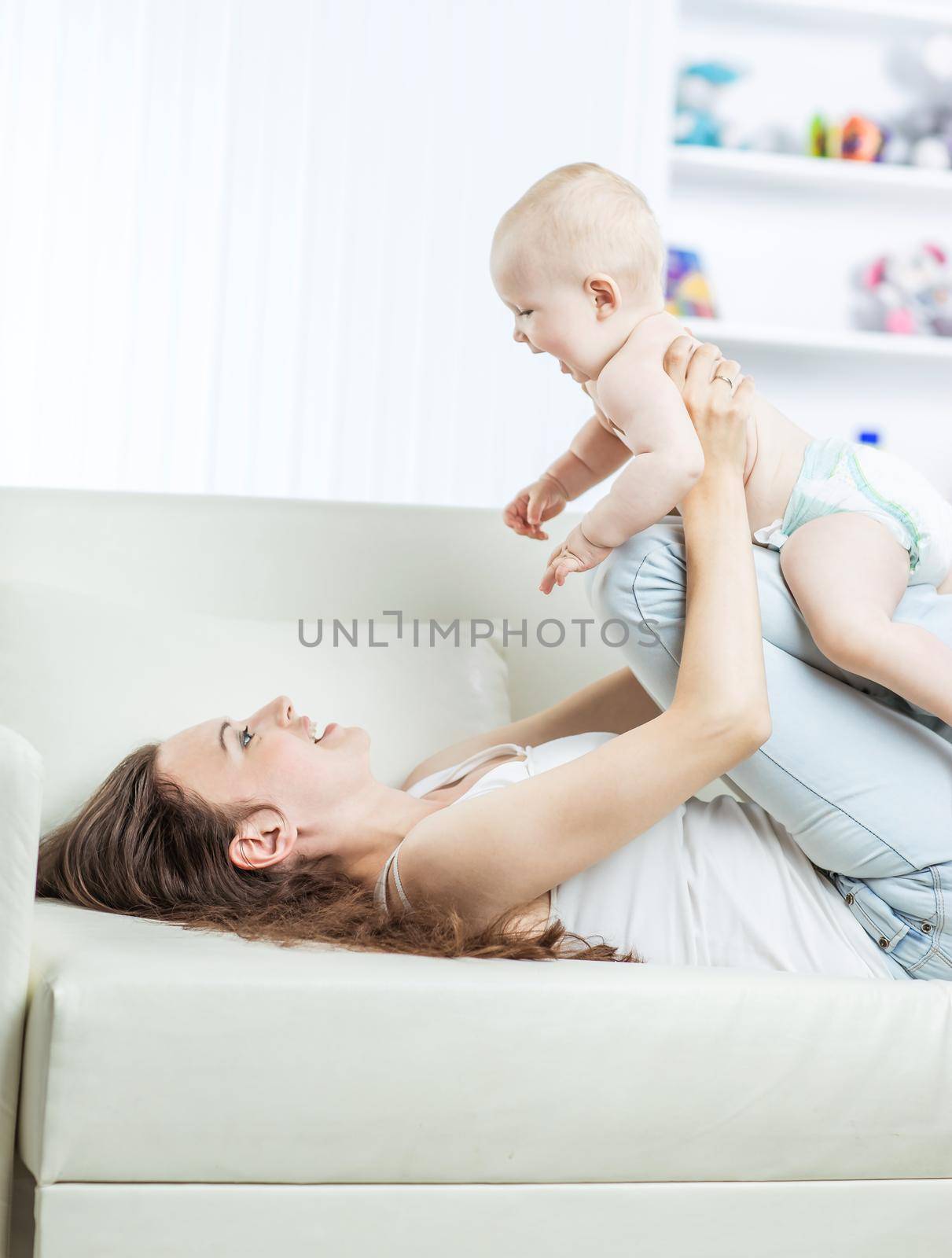 concept of motherhood:happy mother playing with one year old baby in the room for children by SmartPhotoLab