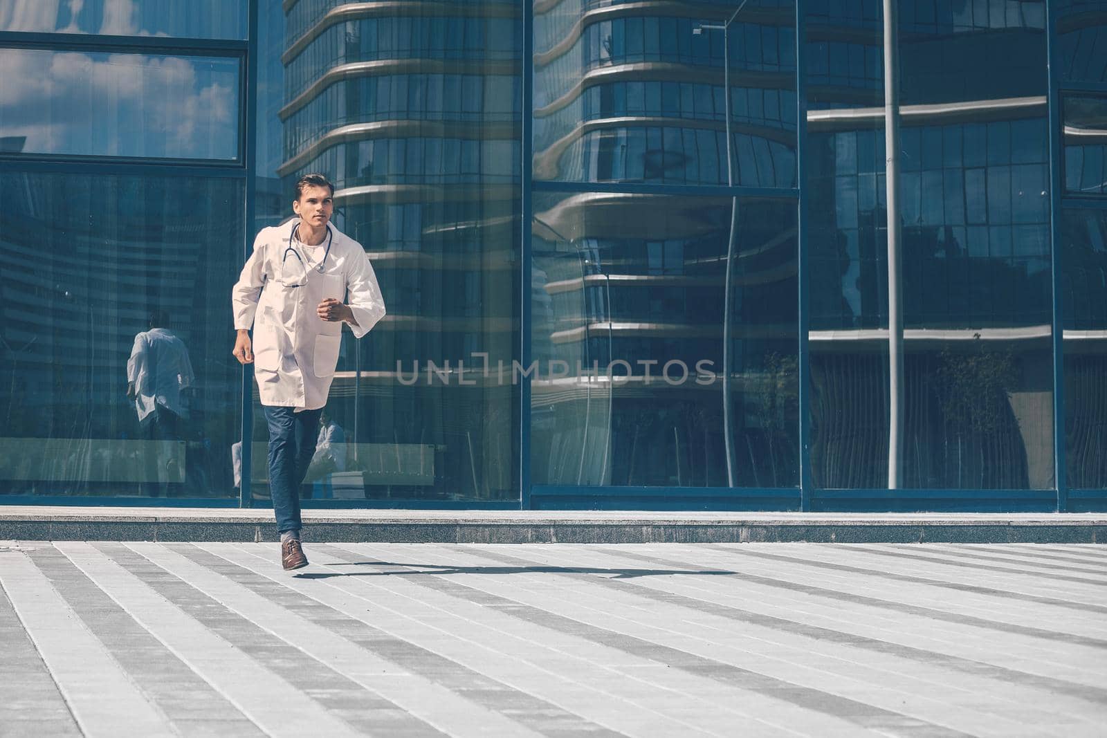 doctor with a stethoscope runs quickly along a city street. photo with a copy-space.