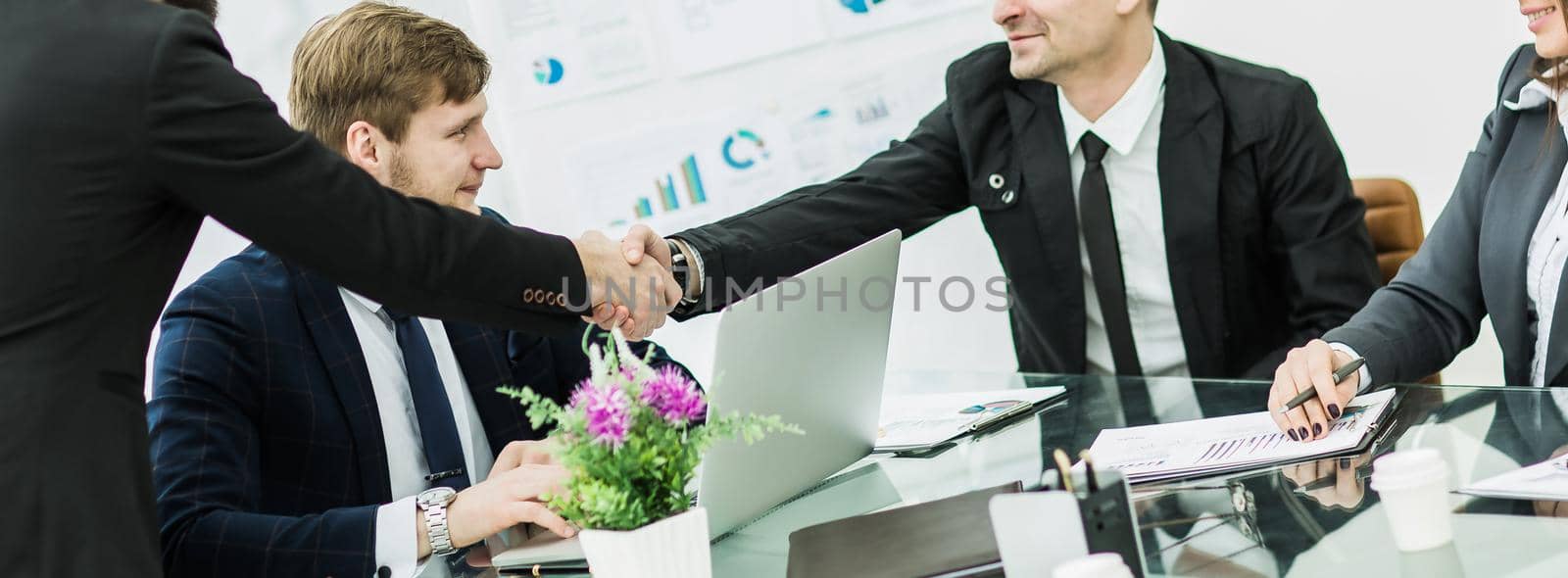 in the foreground - handshake of business partners after signing the contract in the workplace in a modern office.