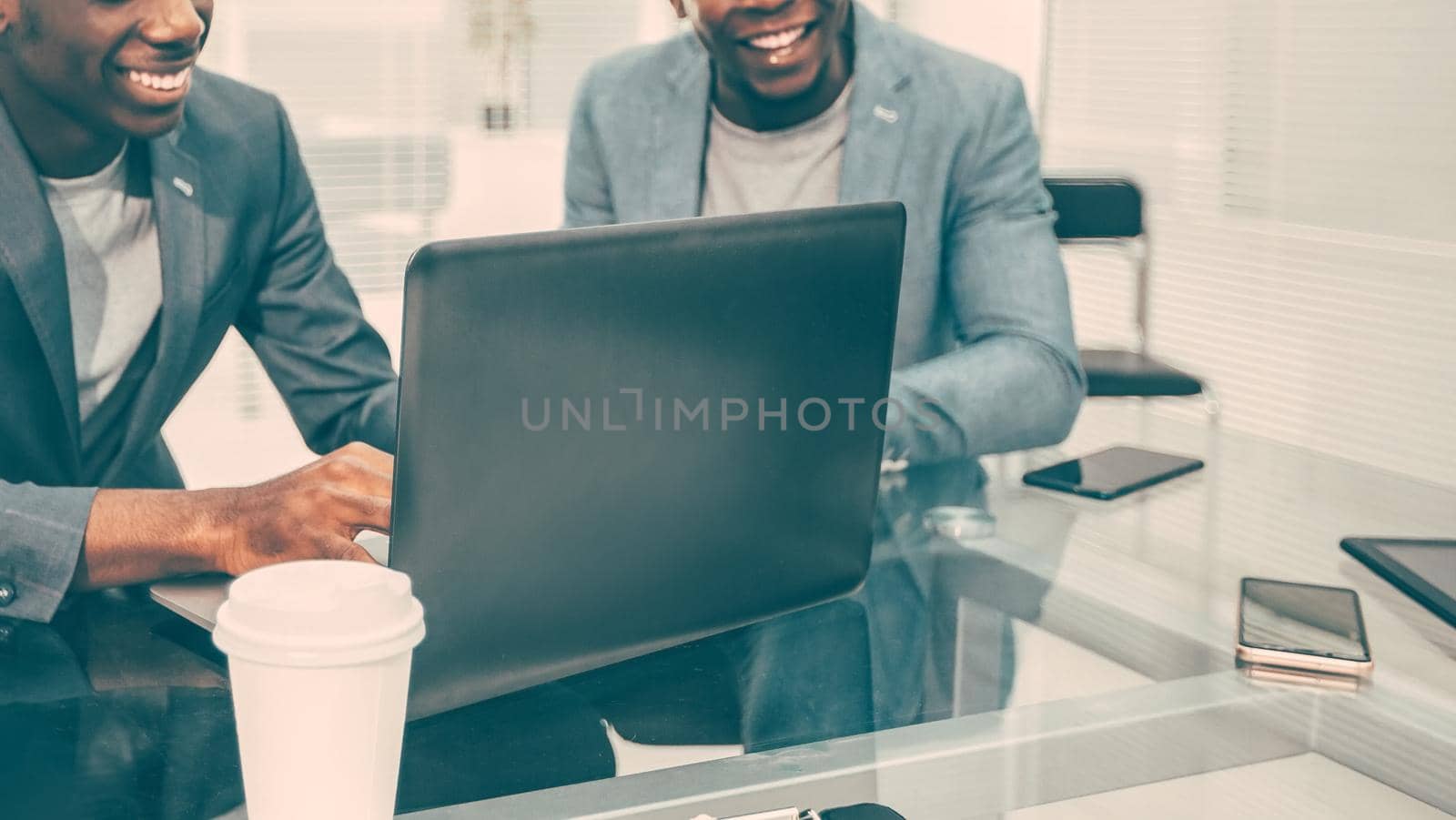 smiling colleagues looking at work on a laptop in the office. photo with copy-space