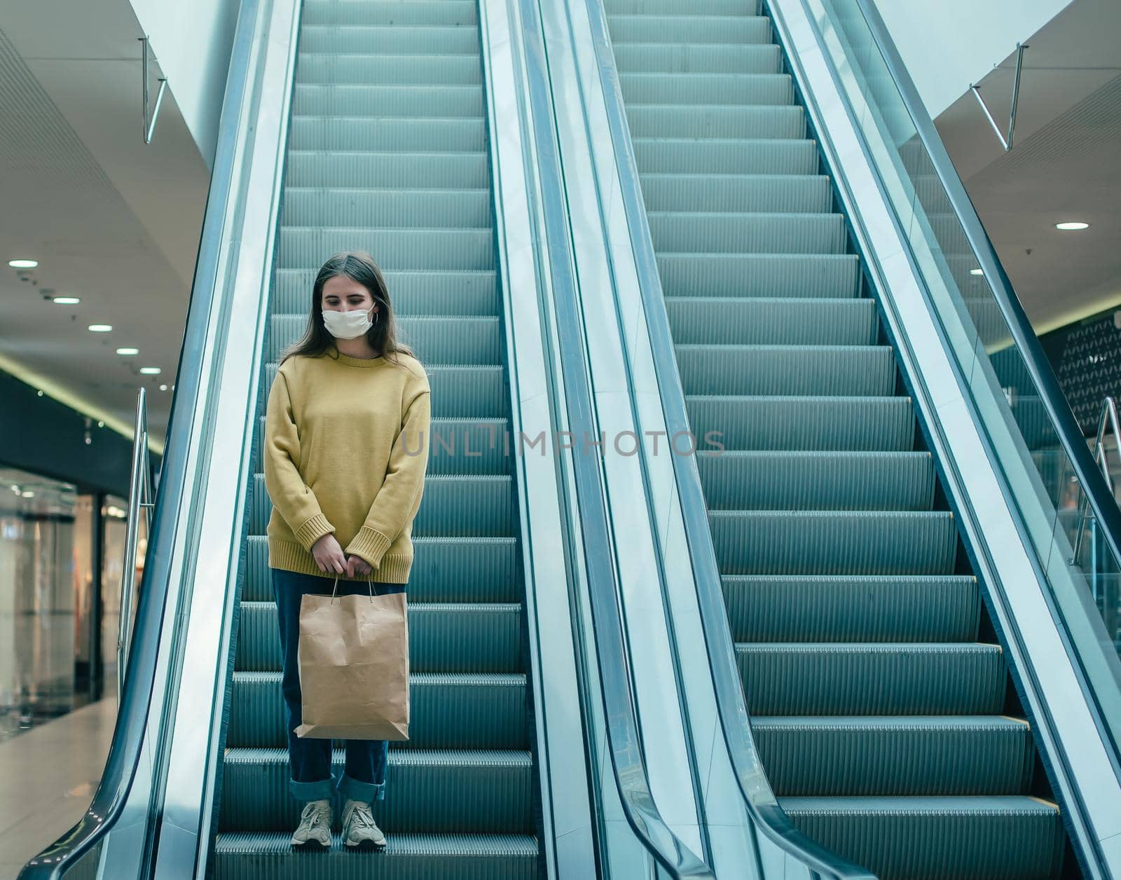 young woman in a protective mask moving around in a shopping center by SmartPhotoLab