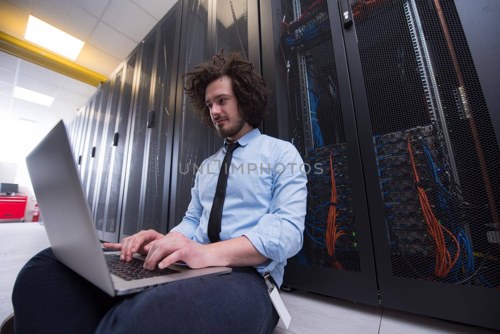 Male IT engineer working on a laptop in server room at modern data center