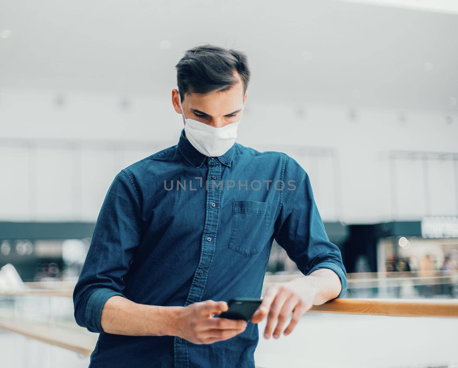 man in a protective mask with a smartphone standing on the street . photo with a copy of the space