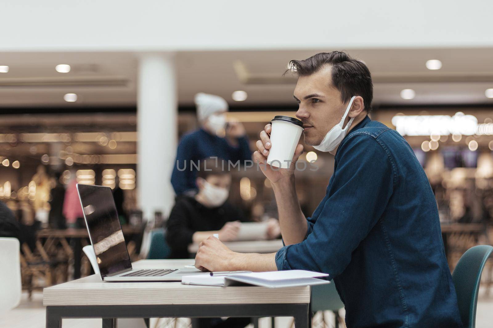 young man with a coffee takeaway sitting at a cafe table . photo with a copy-space