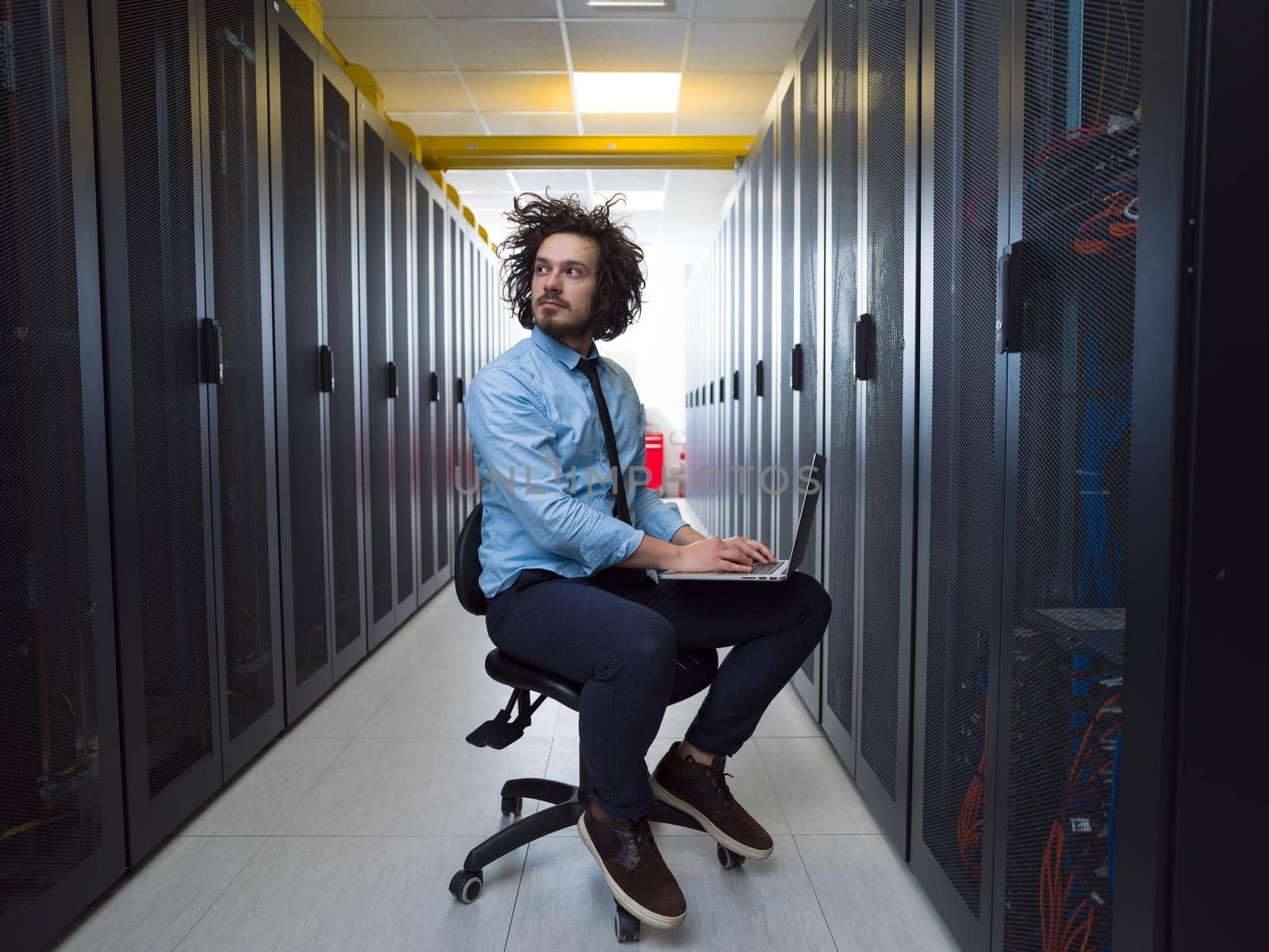 engineer working on a laptop in server room by dotshock