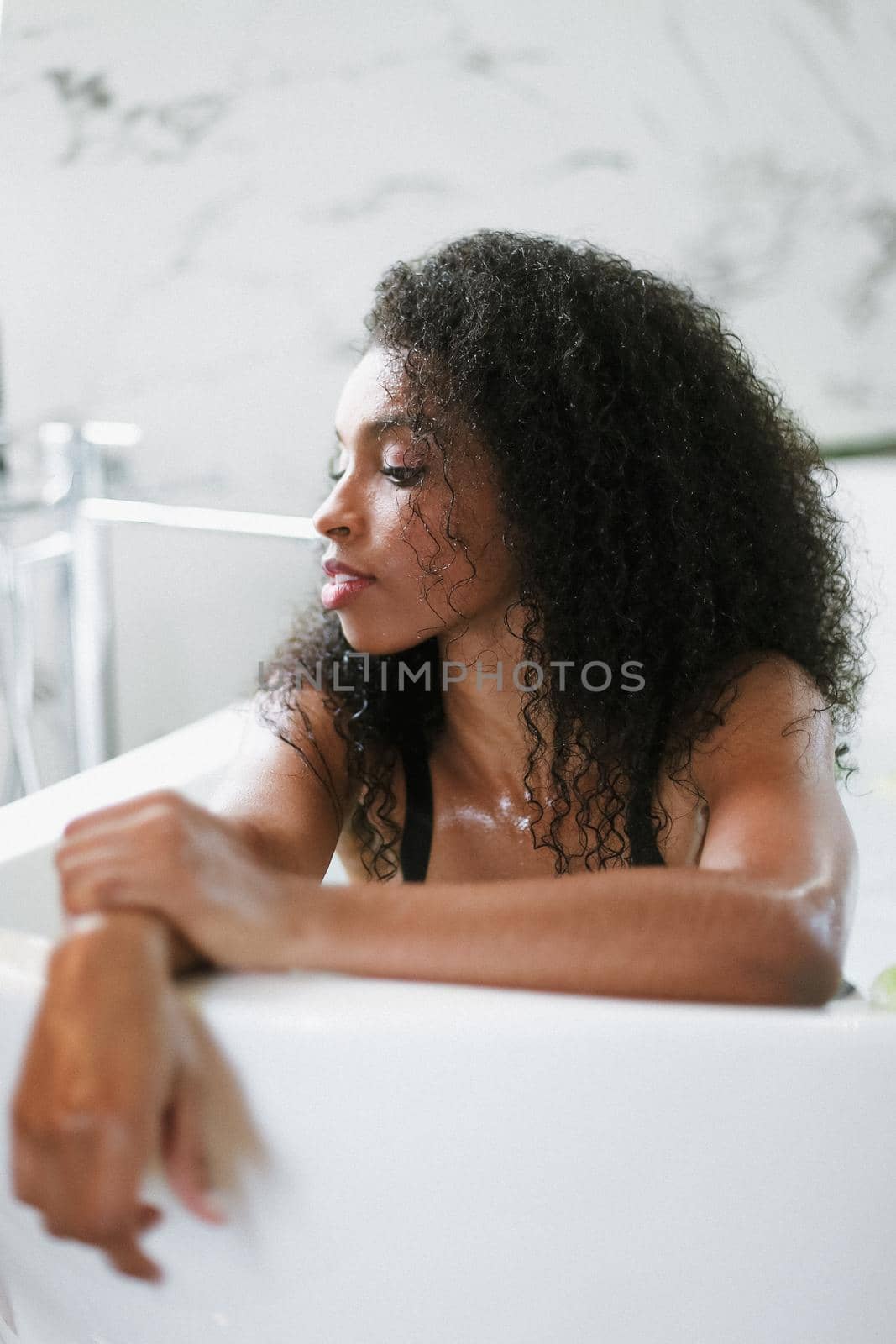 Young brown skin woman lying in barth and wearing black underwear. Concept of personal care and relax.