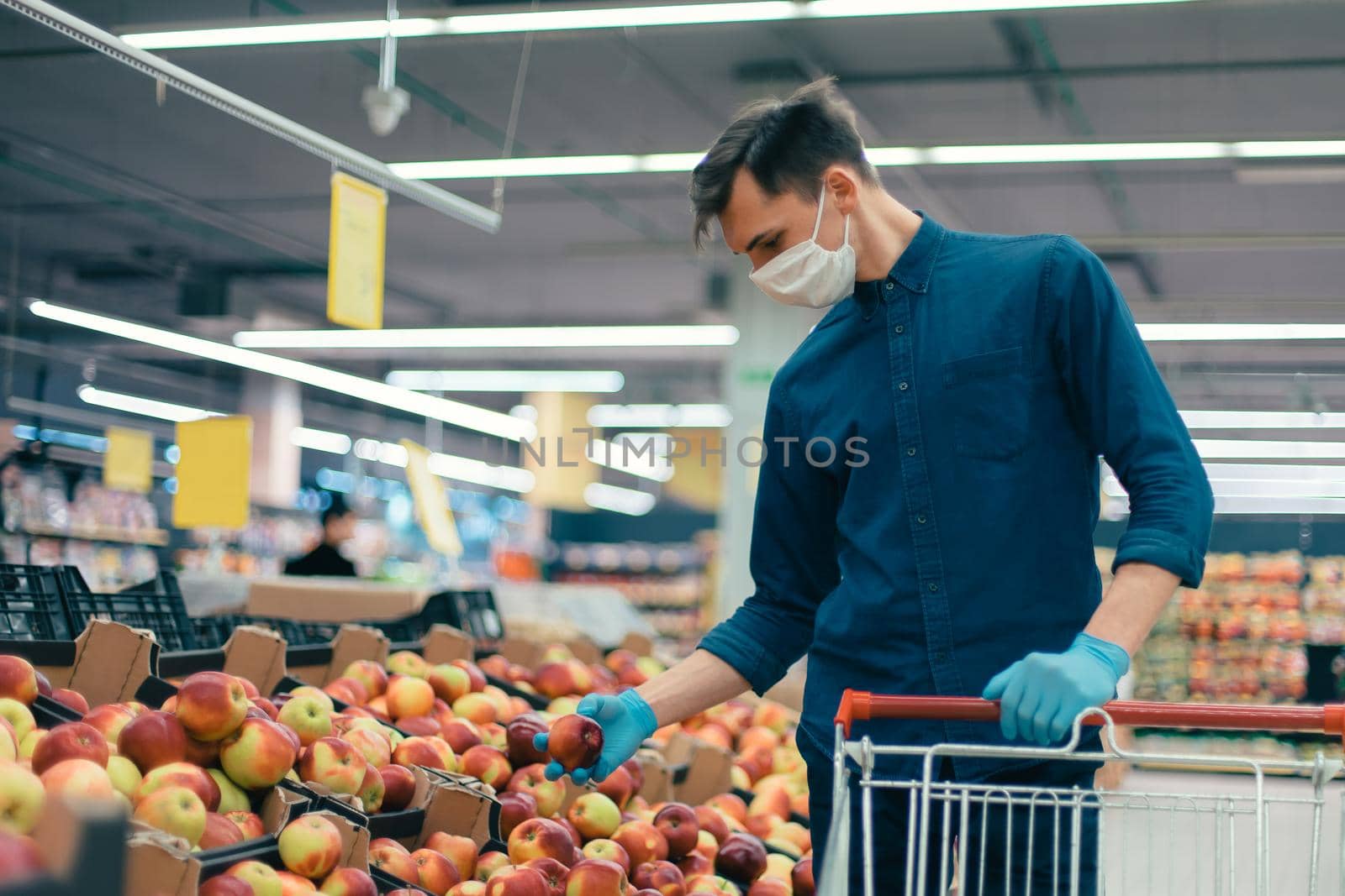 young man in a protective mask standing near the counter with apples. photo with a copy of the space