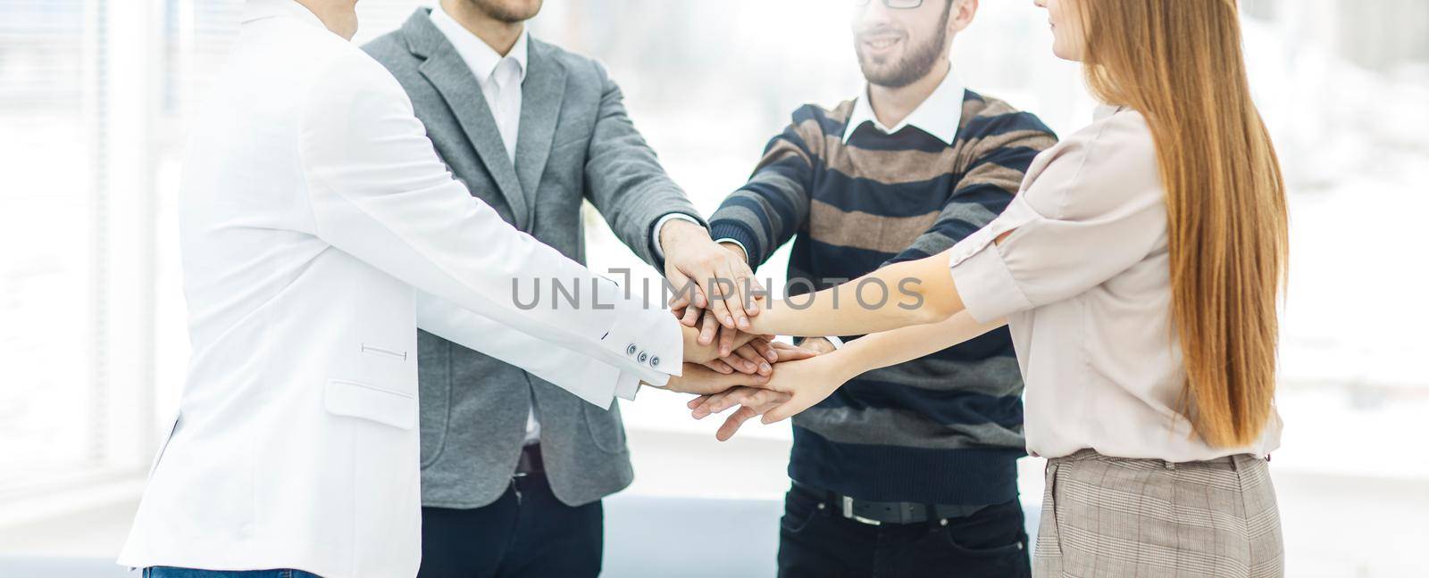 concept of success in business: friendly business team standing in a circle and joining his hands together by SmartPhotoLab