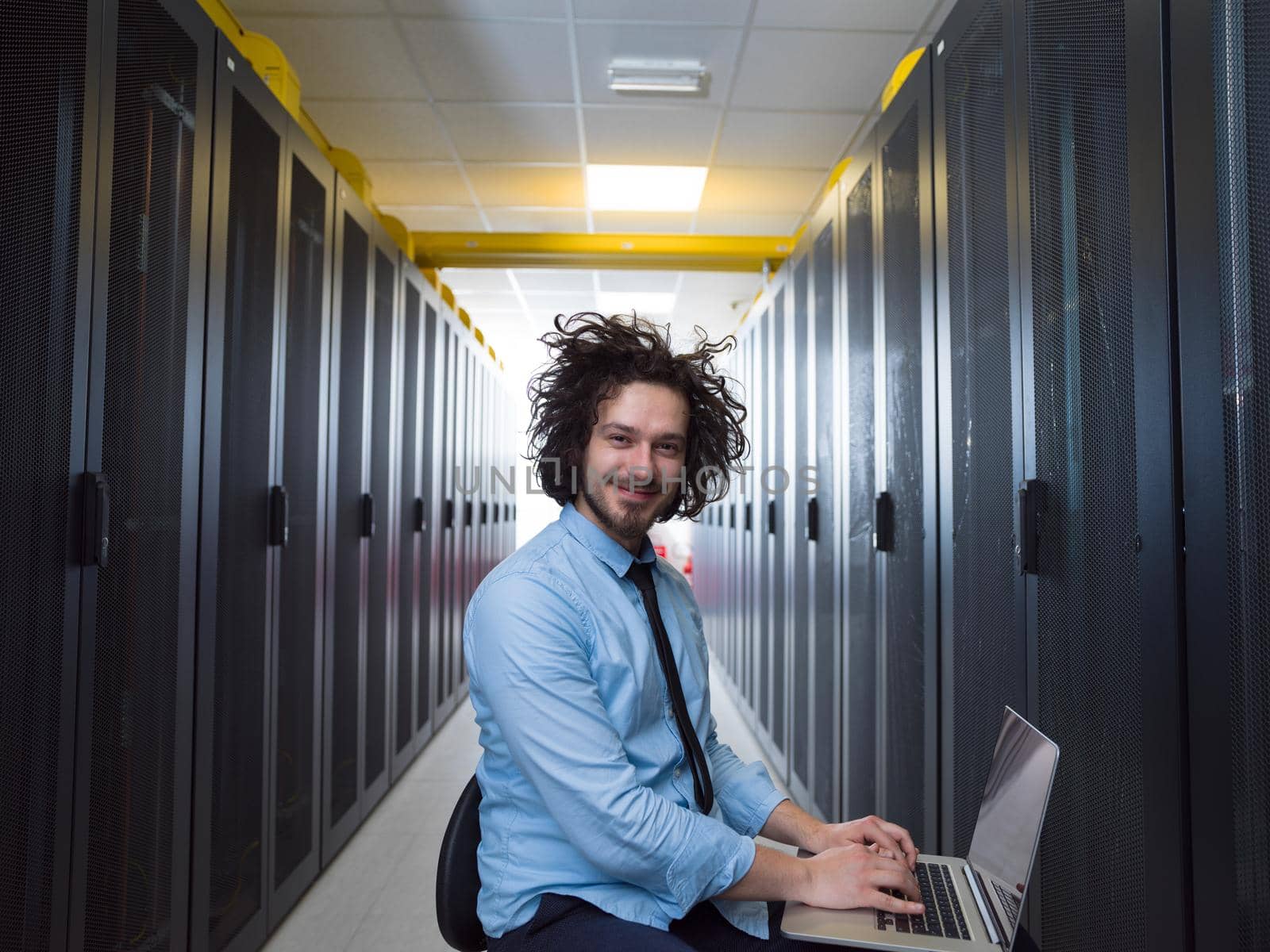 Male IT engineer working on a laptop in server room at modern data center