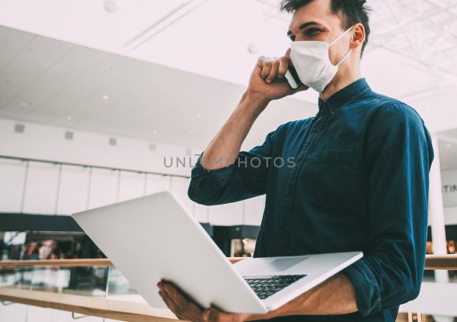 young man in a protective mask talking on a smartphone. by SmartPhotoLab