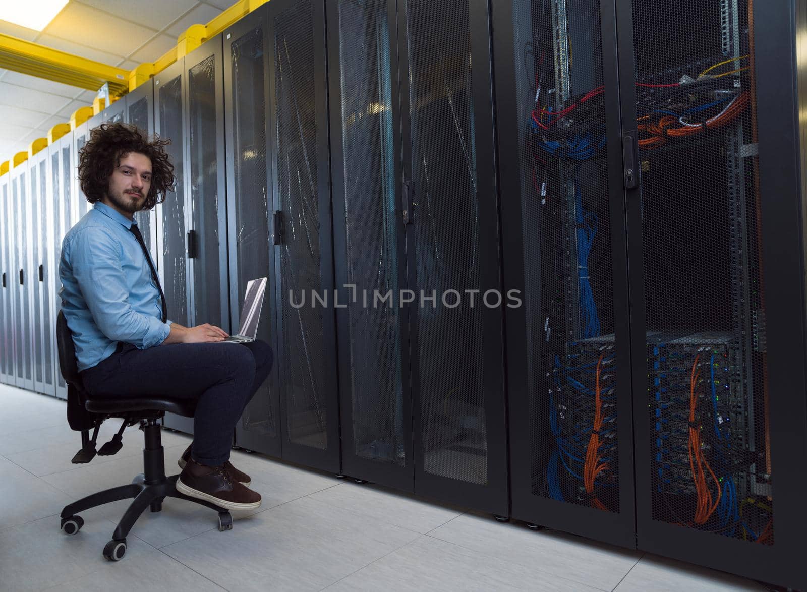 engineer working on a laptop in server room by dotshock