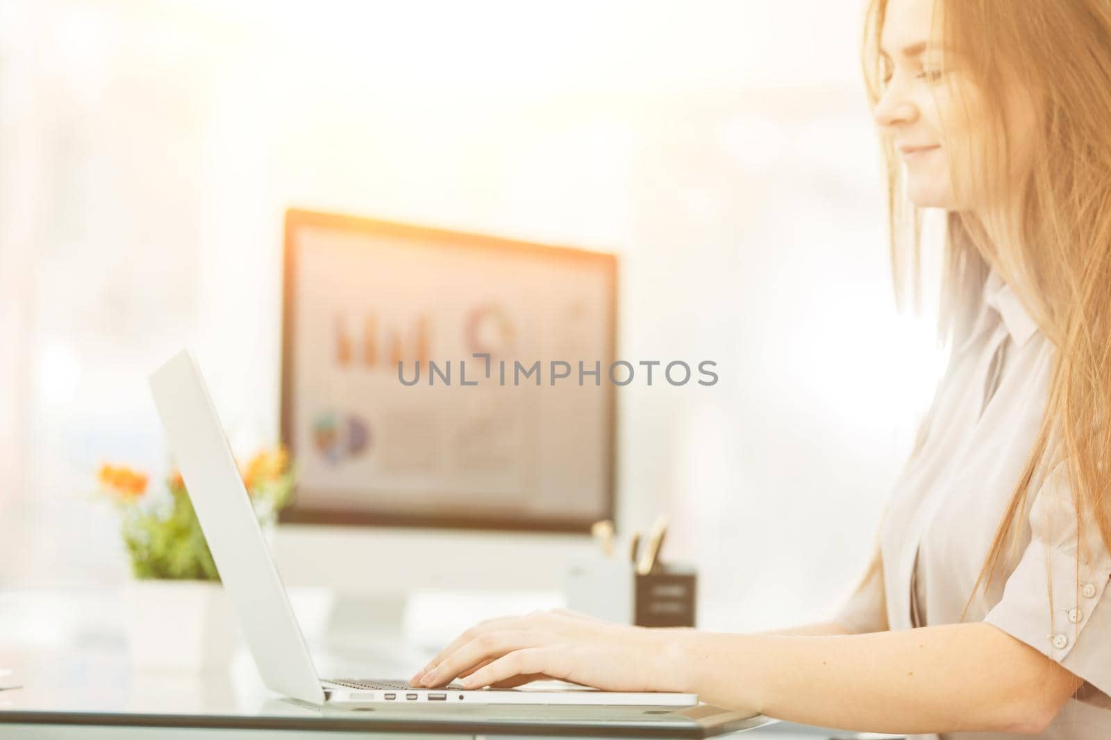 accountant working on a laptop with financial charts on the desktop. by SmartPhotoLab