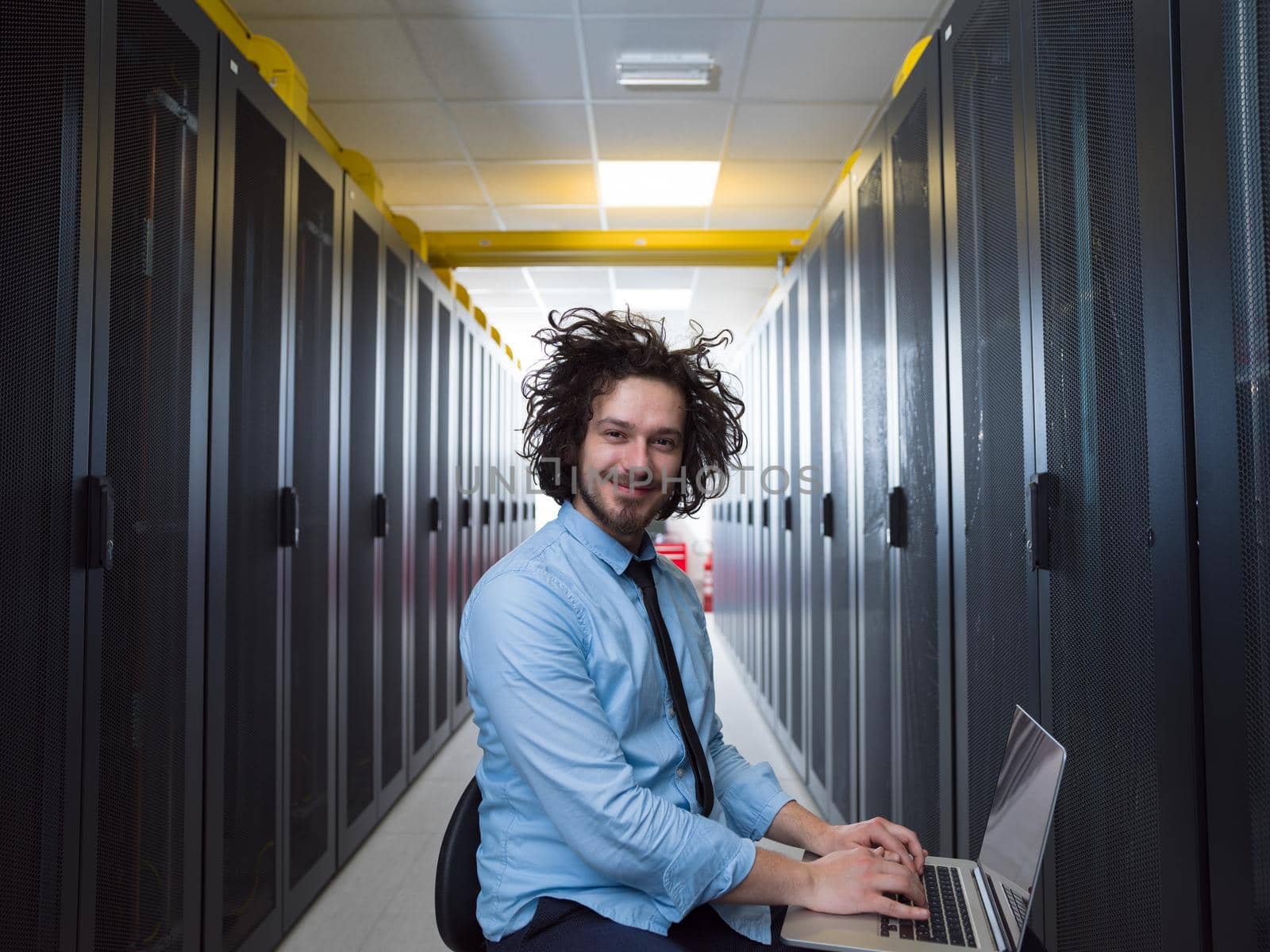 engineer working on a laptop in server room by dotshock