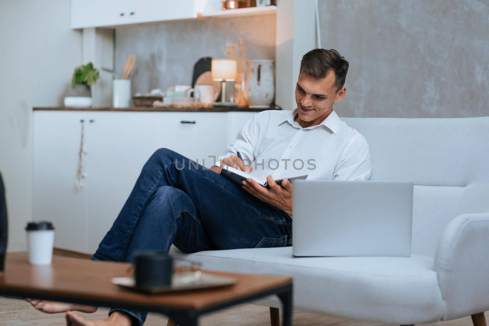 young man taking notes sitting on the couch . photo with a copy-space.