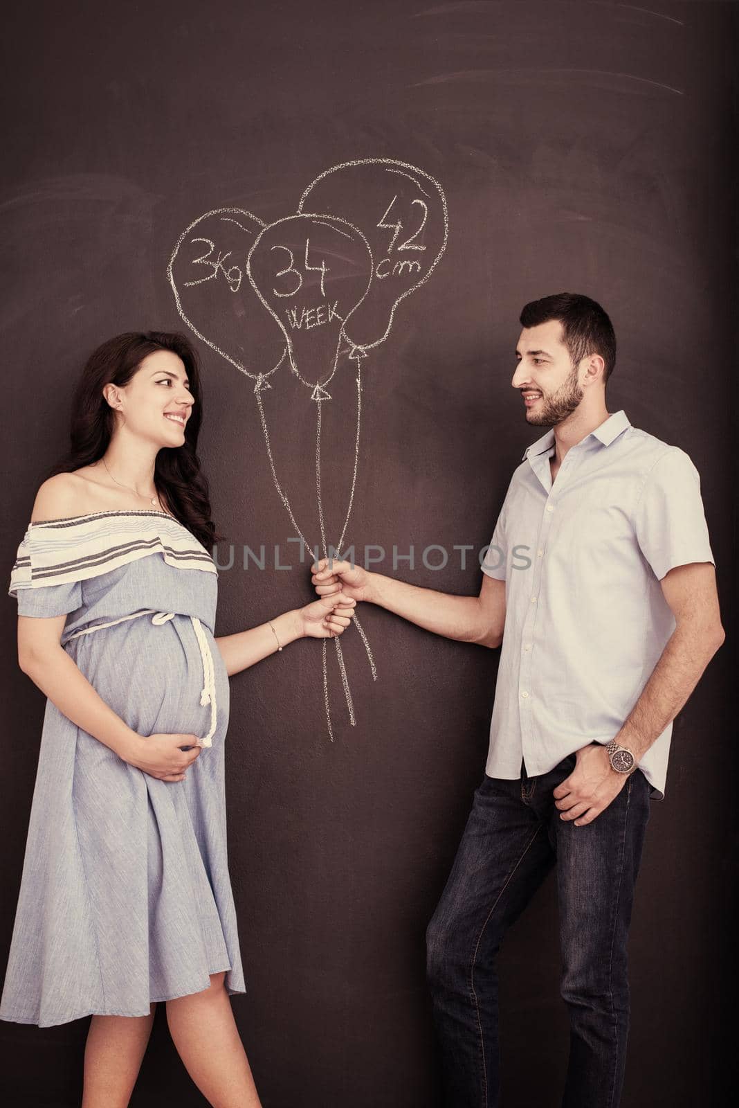 pregnant couple drawing their imaginations on chalk board by dotshock