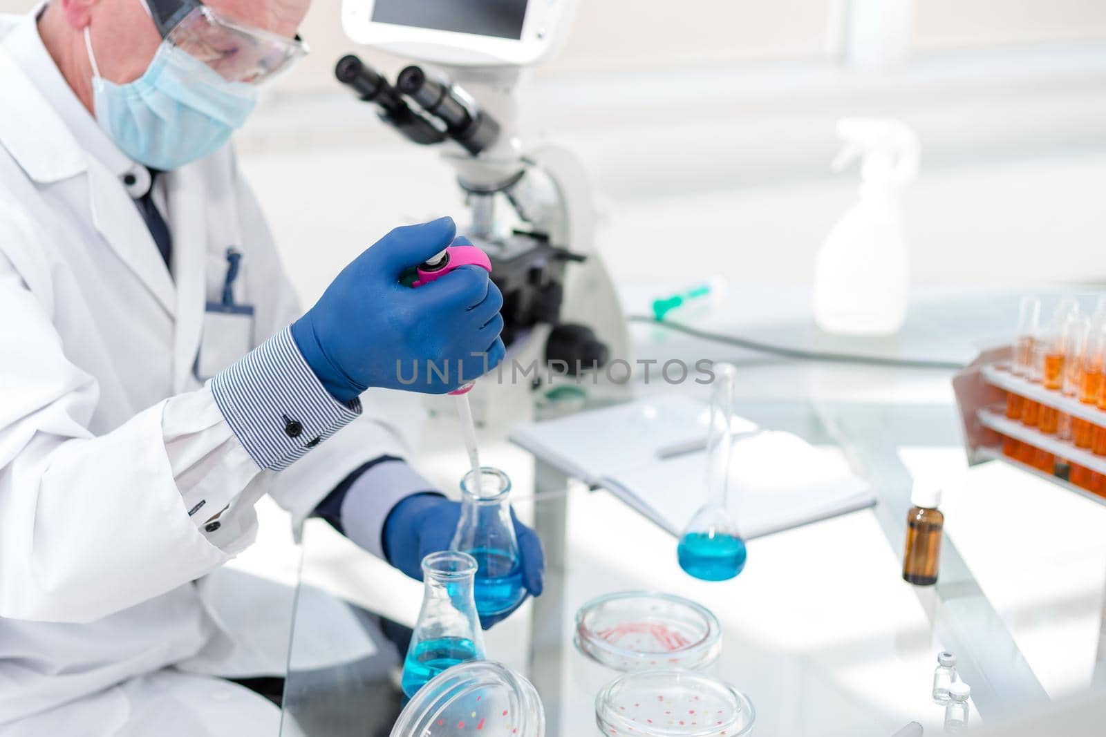 employees of the scientific laboratory examining the liquid in a laboratory flask . by SmartPhotoLab