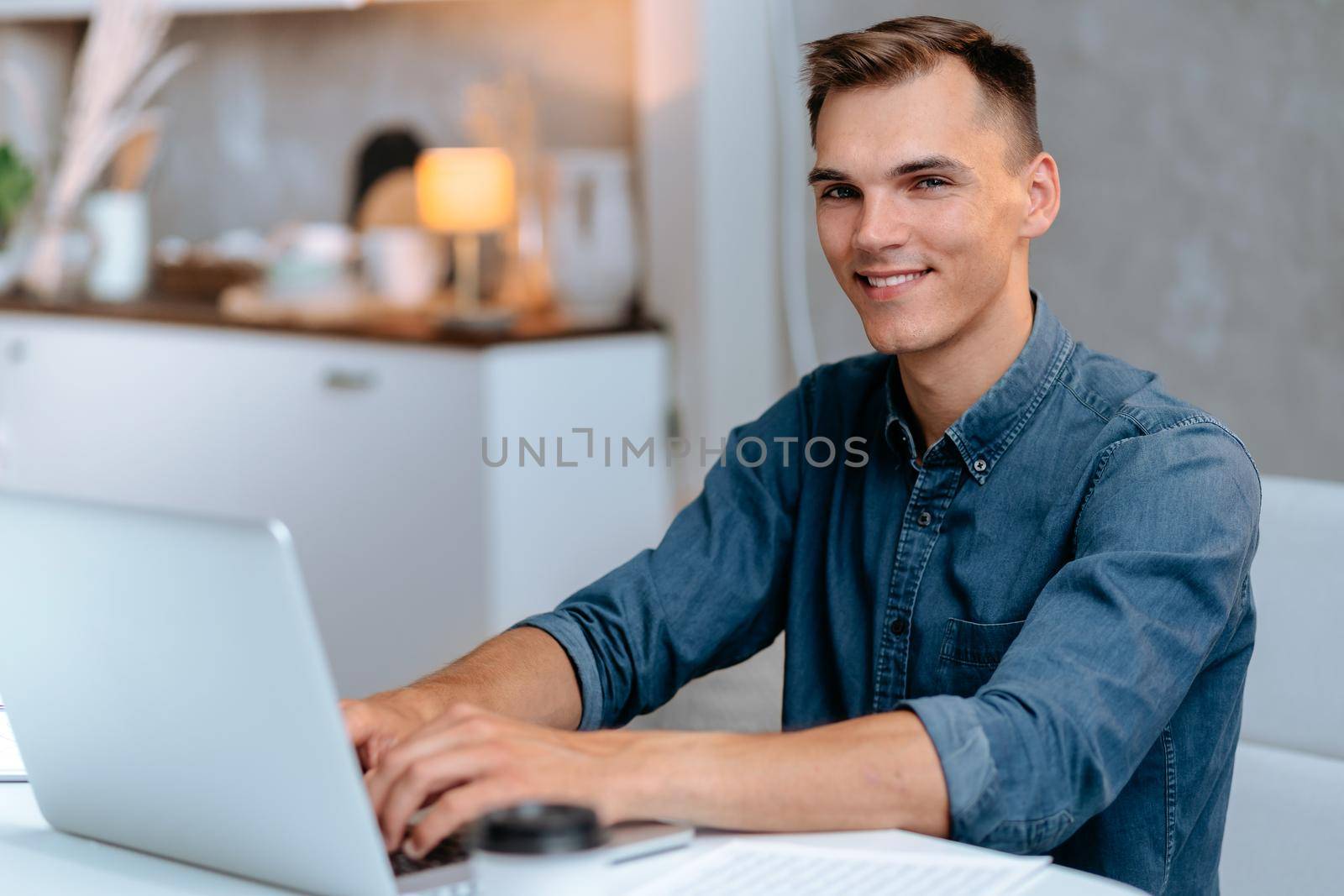 male freelancer works on a laptop in his kitchen. by SmartPhotoLab