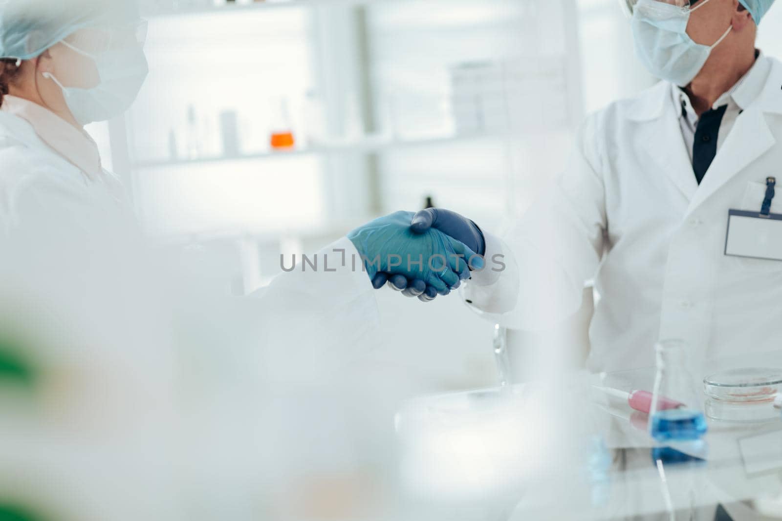 close up. scientists colleagues shaking hands with each other. science and health.