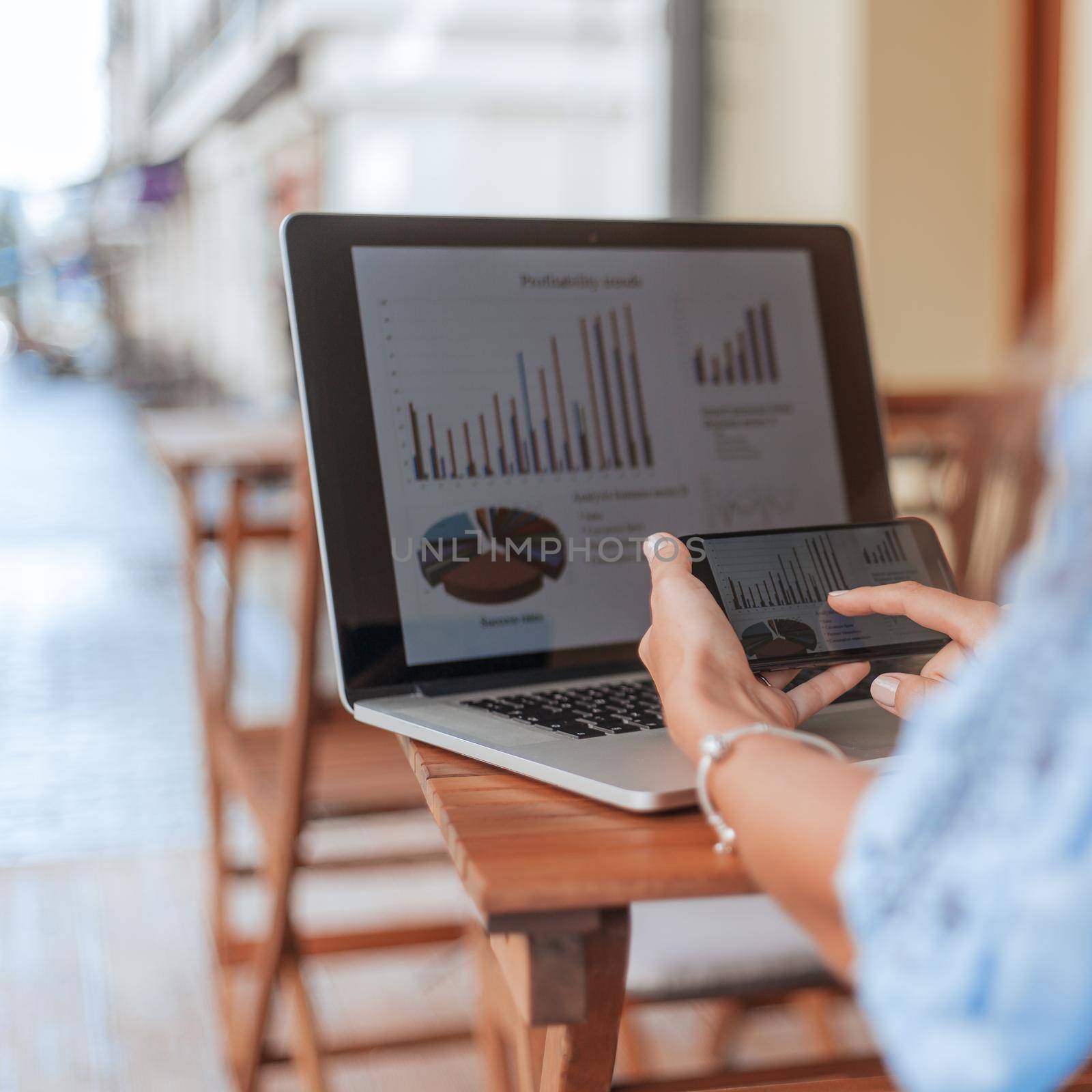 businesswoman with a smartphone analyzing financial data. by SmartPhotoLab