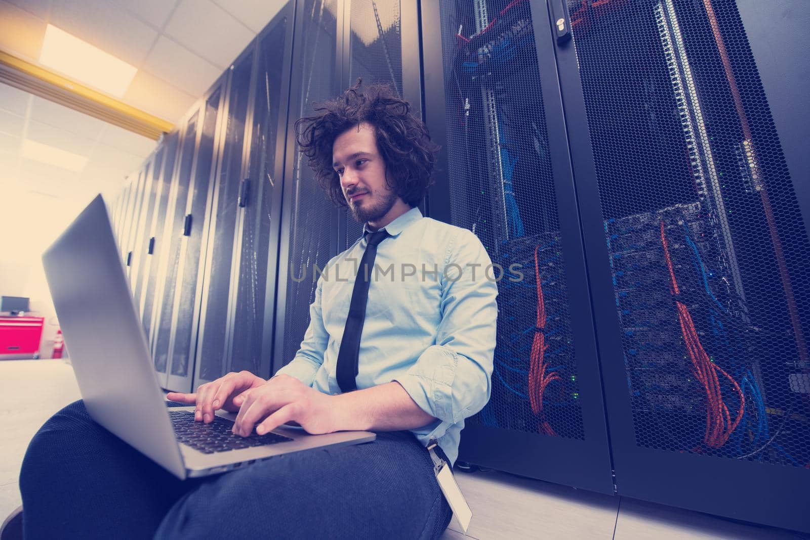 Male IT engineer working on a laptop in server room at modern data center