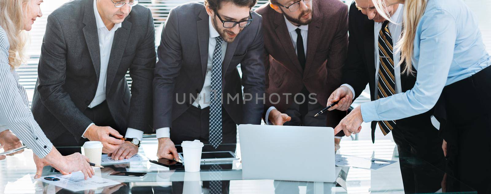 group of employees looking at the laptop screen with interest by SmartPhotoLab