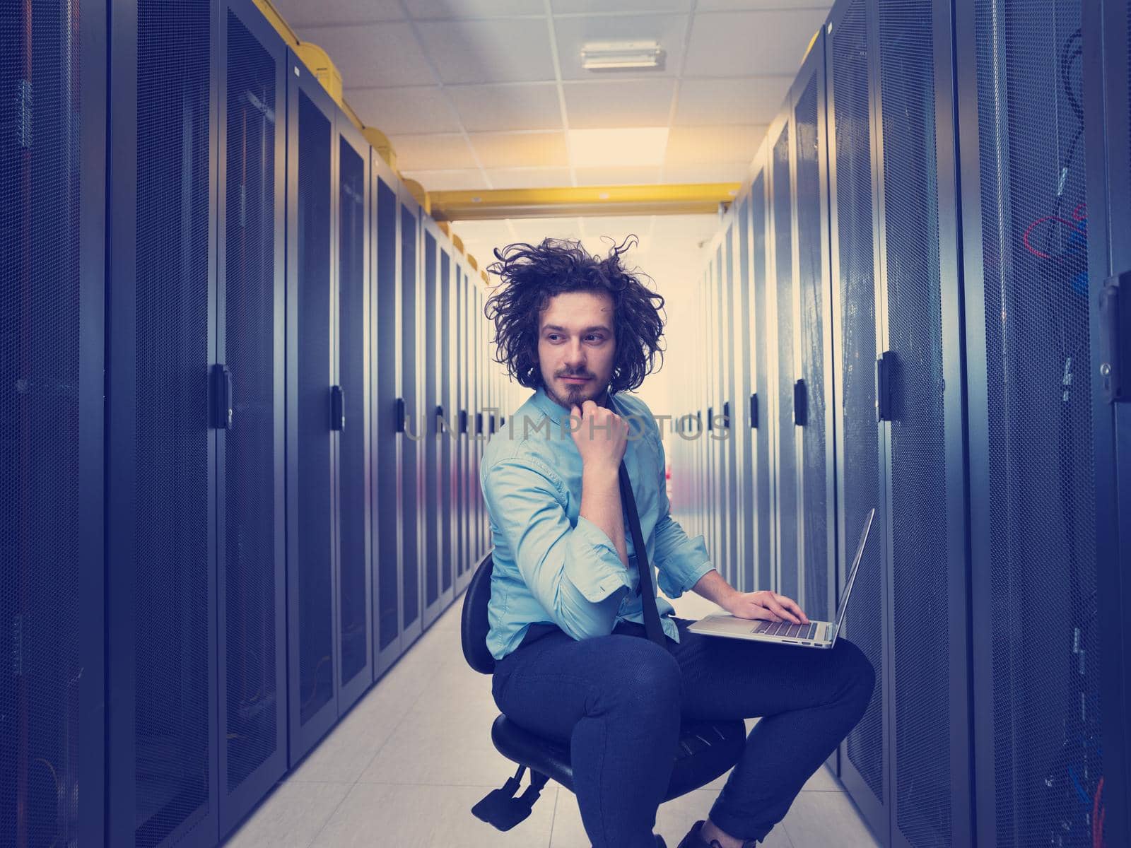 Male IT engineer working on a laptop in server room at modern data center