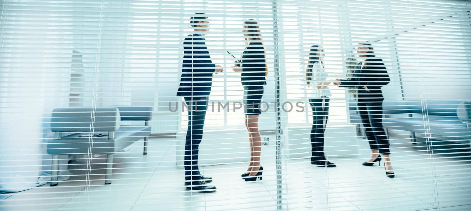 through the blinds. employees discussing work issues in the office. office workdays