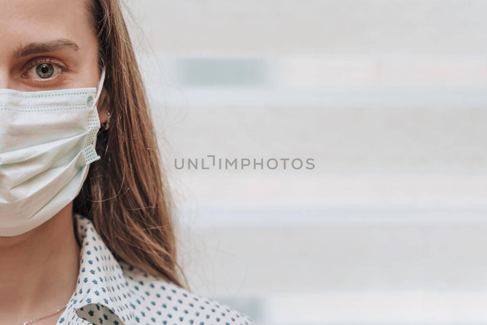 Close-up portrait of a young blonde woman in a medical mask on a light background. Virus protection. Coronovirus covid-19 The concept of a pandemic epidemic. Quarantine. Stay at home. by Matiunina