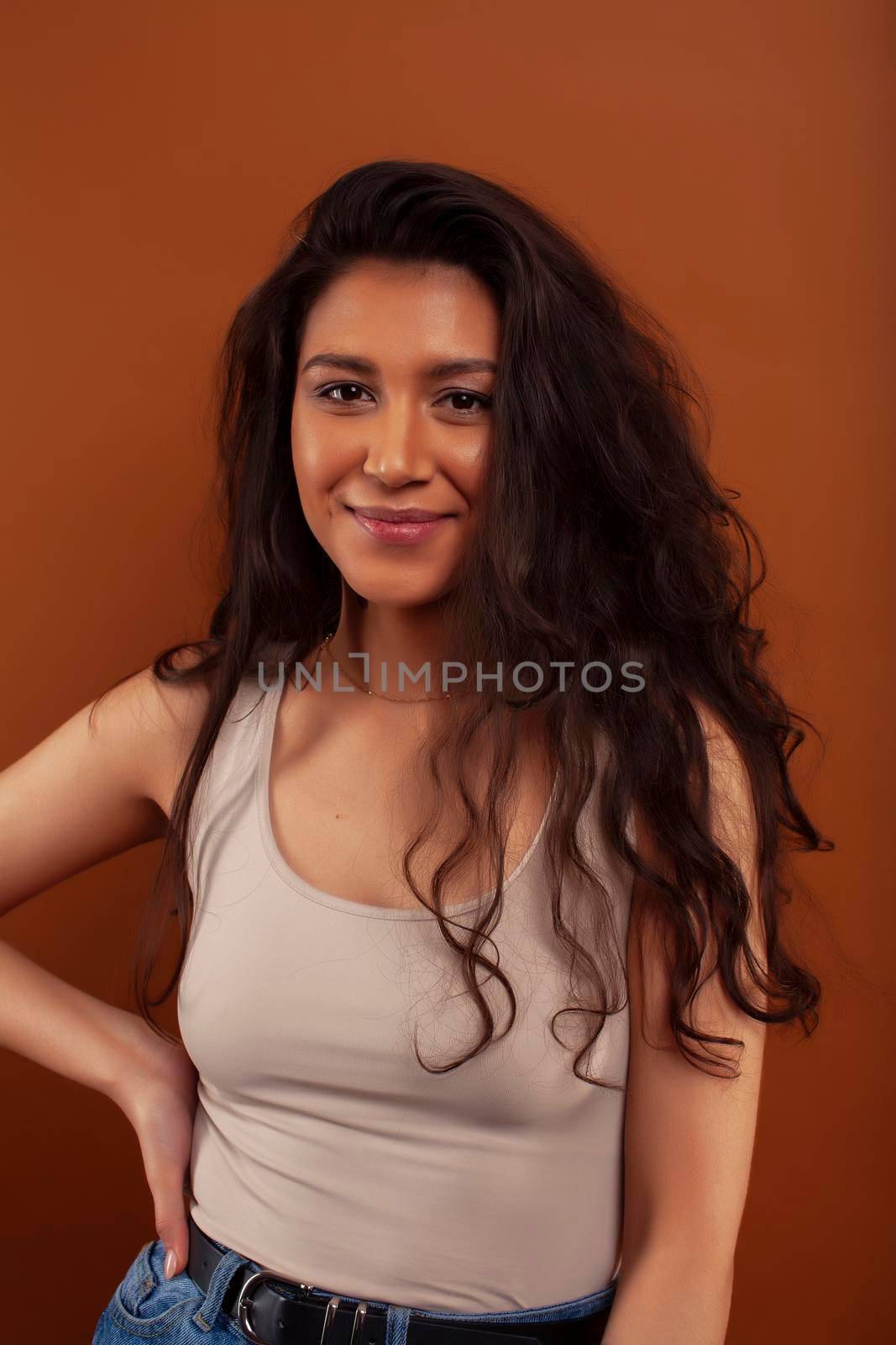 cute happy young indian woman posing cheerful on brown background in studio closeup smiling, fashion beauty