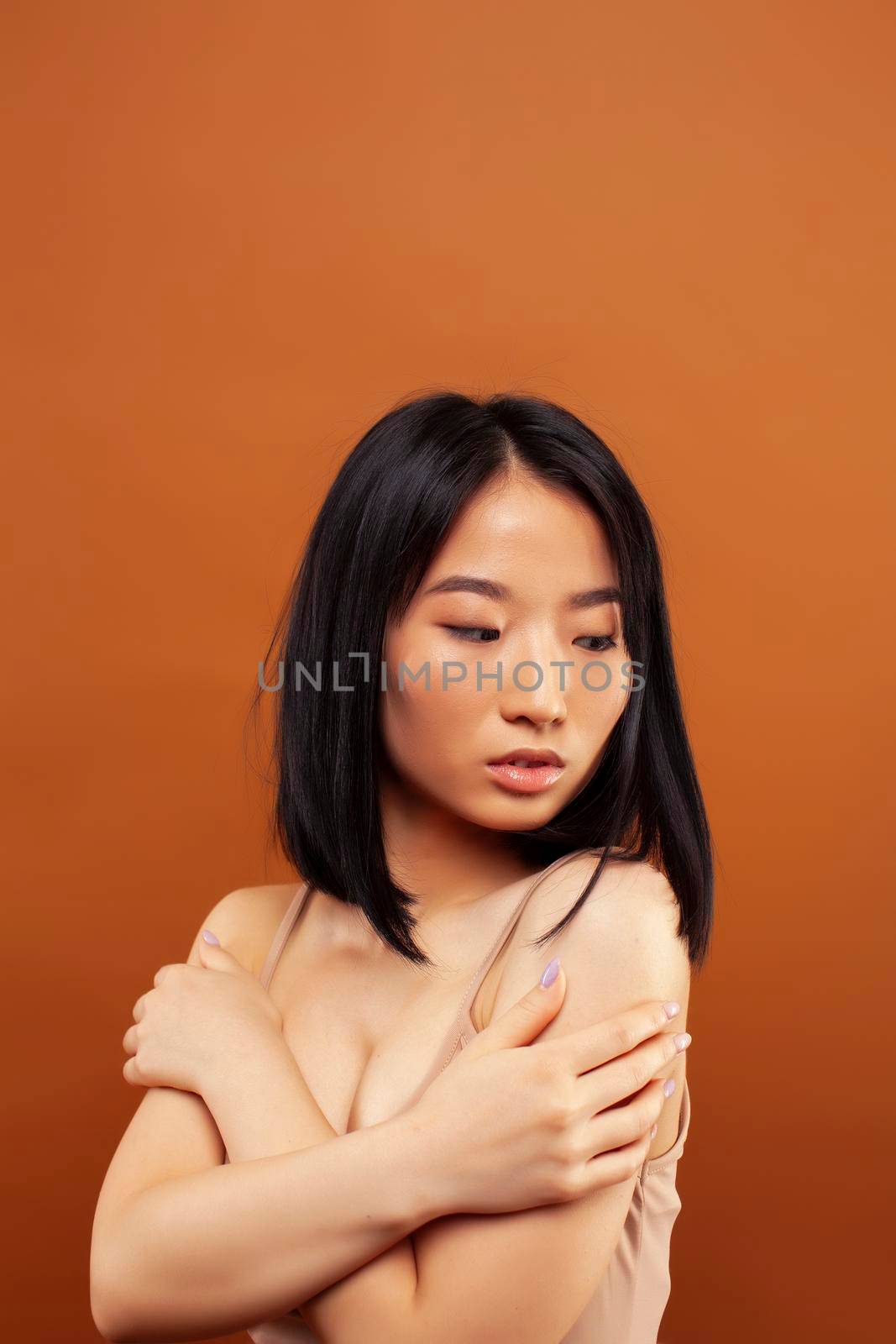 young pretty asian woman cheerful smiling posing on warm brown background, lifestyle people concept by JordanJ
