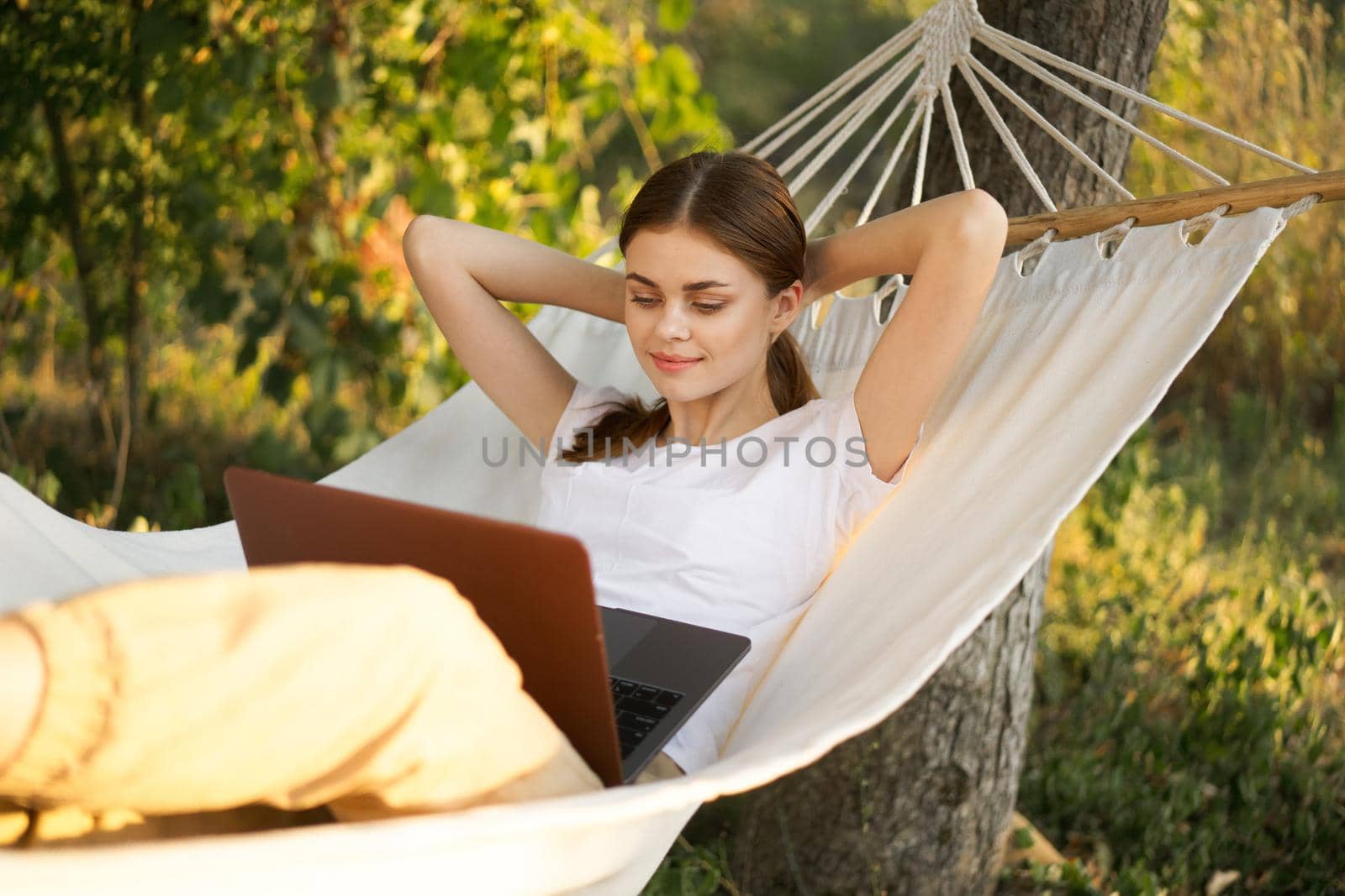 woman lies on a hammock with laptop travel vacation internet by Vichizh