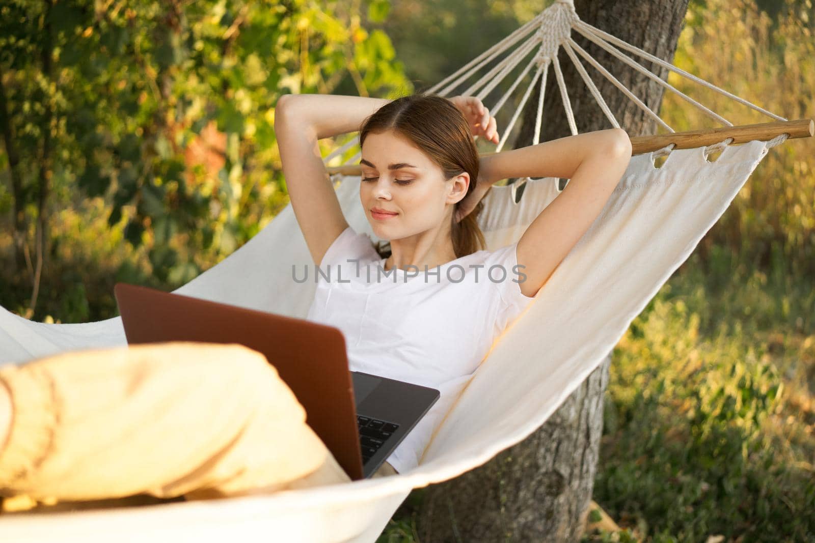 woman lies on a hammock with laptop travel vacation internet by Vichizh