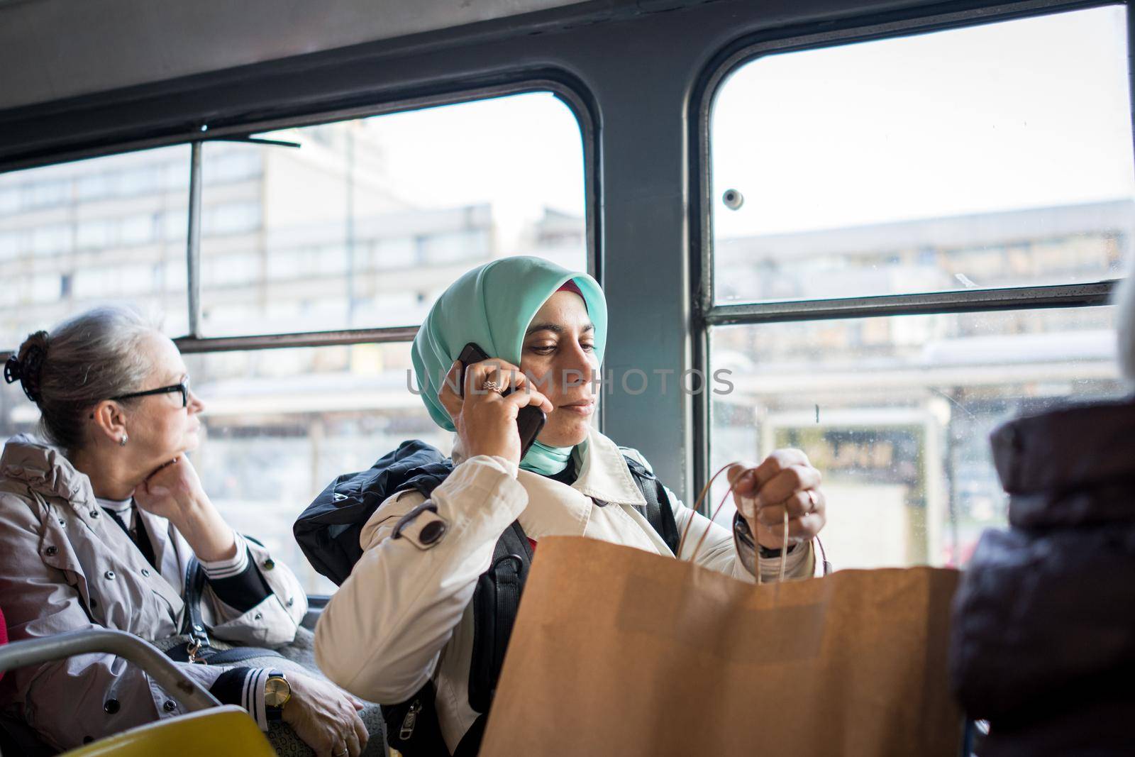 Muslim woman riding public transport in city by Zurijeta
