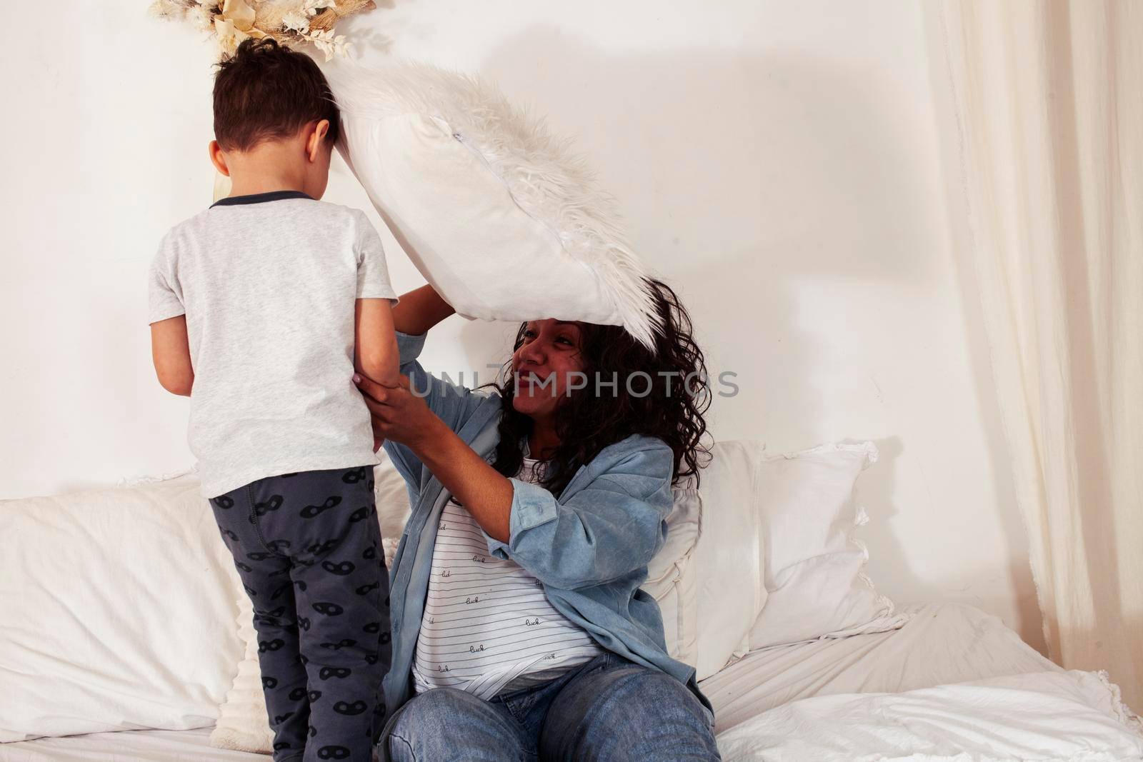 young pretty african american mother with son in bed at morning playing, happy family, lifestyle people concept by JordanJ