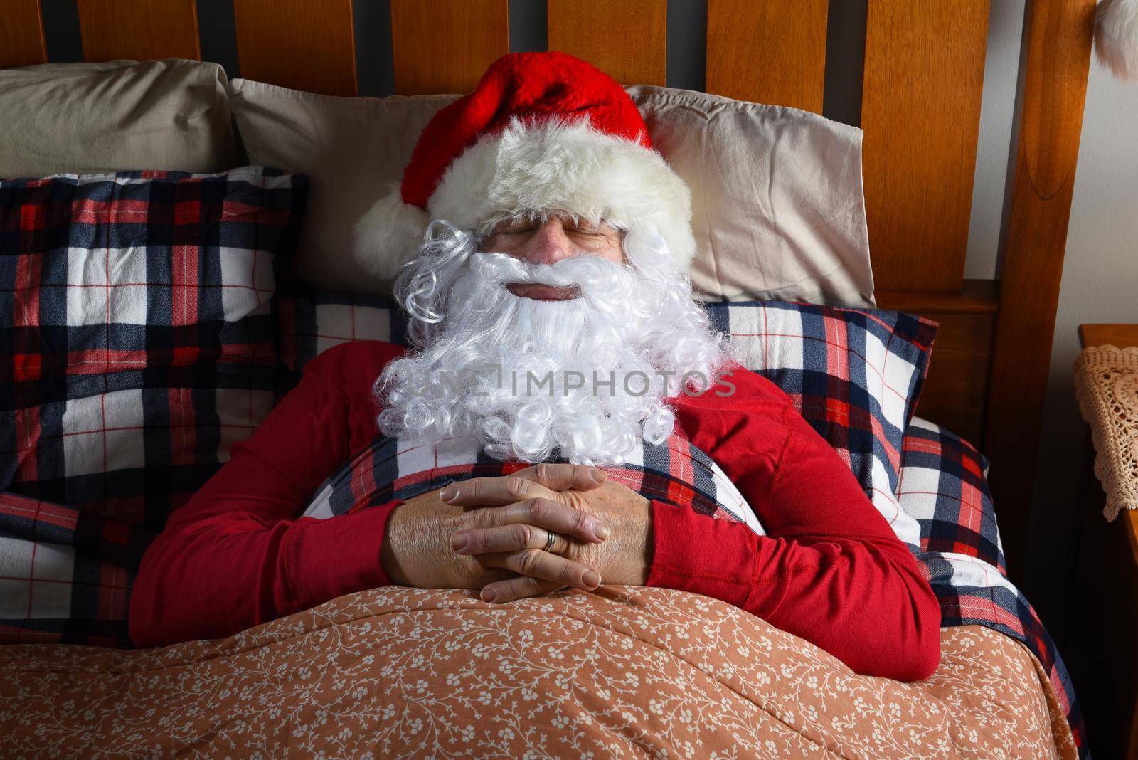 Santa Claus sleeping in his bed at the North Pole, with his hands folded on his chest, After His Christmas Eve deliveries.