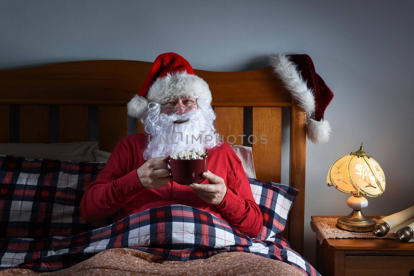 Santa Claus sitting in bed with a large mug of hot cocoa before he goes to sleep on Christmas Eve.