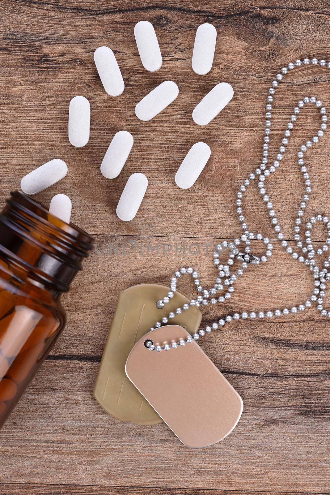 Military and Veterans Health Care Concept. Dog tags and pills on a wood background. by sCukrov