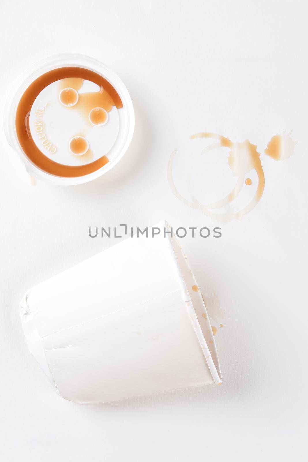 Top view of a crushed paper coffee cup with lid and coffee stains.